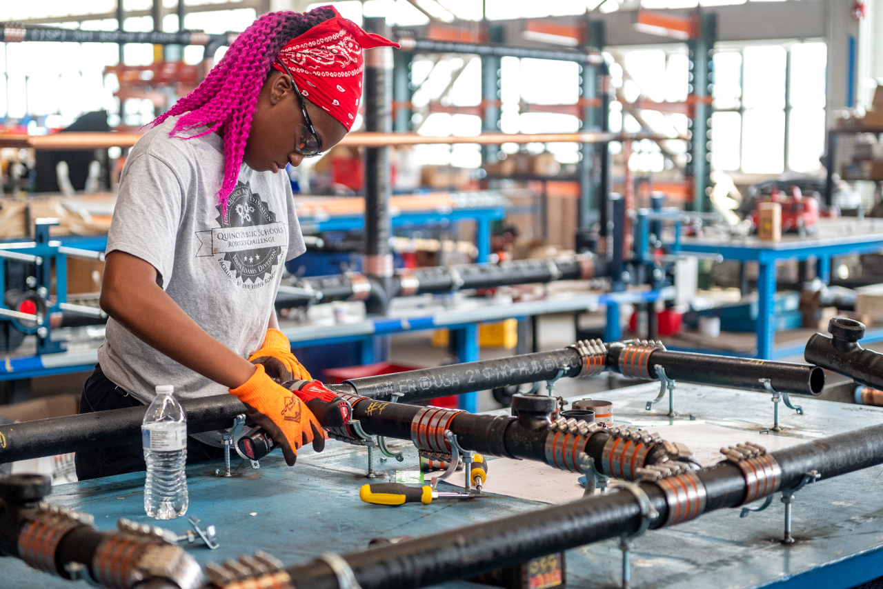 a beautiful girl with pink hair working on metal